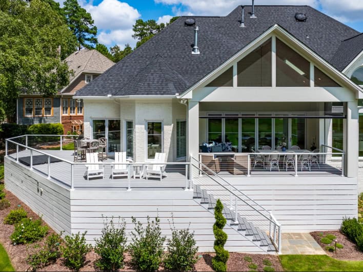 High-end modern house with spacious outdoor deck, stylish patio furniture, and large glass windows showcasing contemporary architectural design.